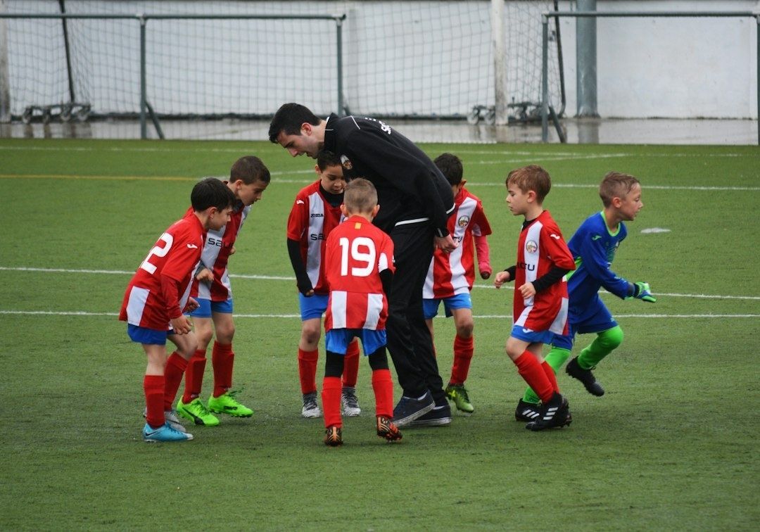 Ungdomsspelare samlas kring en vuxen på fotbollsplanen
